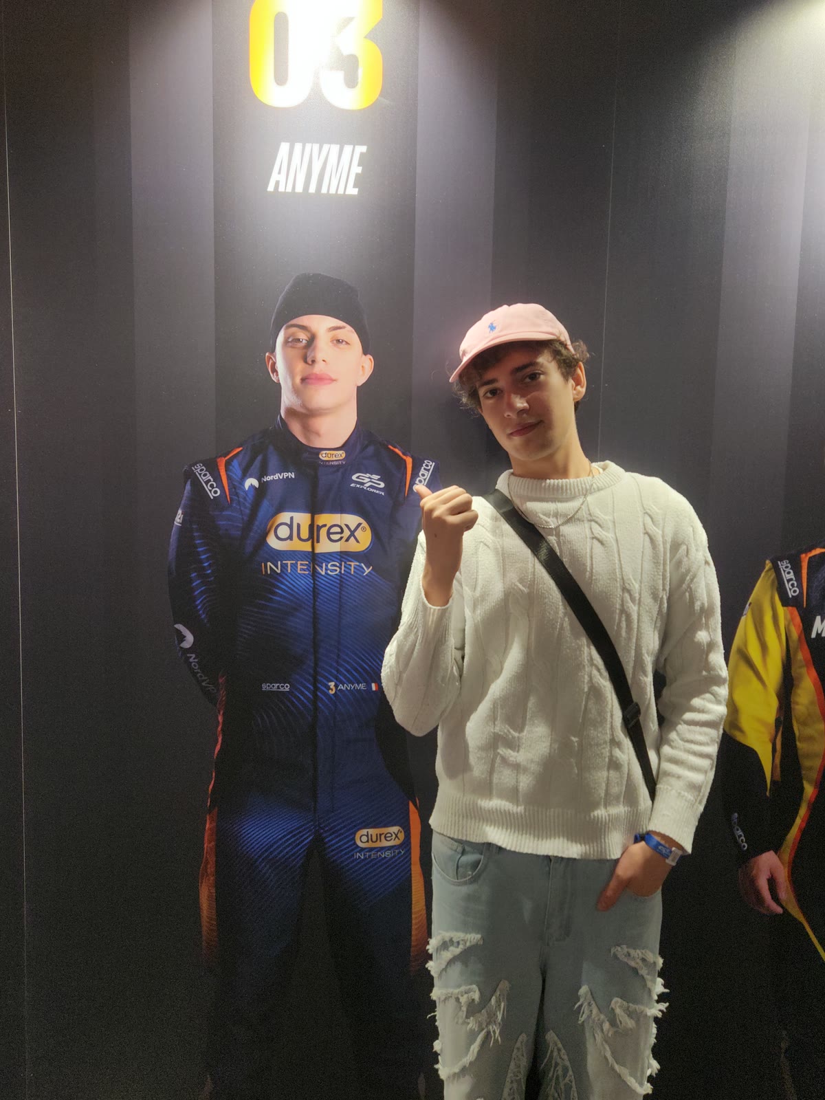 Tyméo SEKKAL, pouce levé, à côté de l'affiche géante du pilote Anyme au GP Explorer
